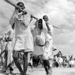 An injured woman is carried by her male relations