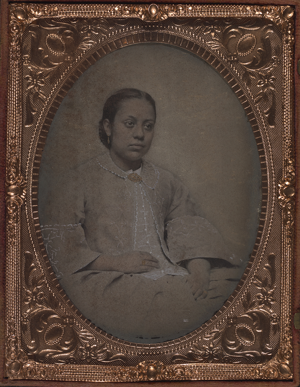 Photographic portrait of a biracial woman seated with hands resting in her lap