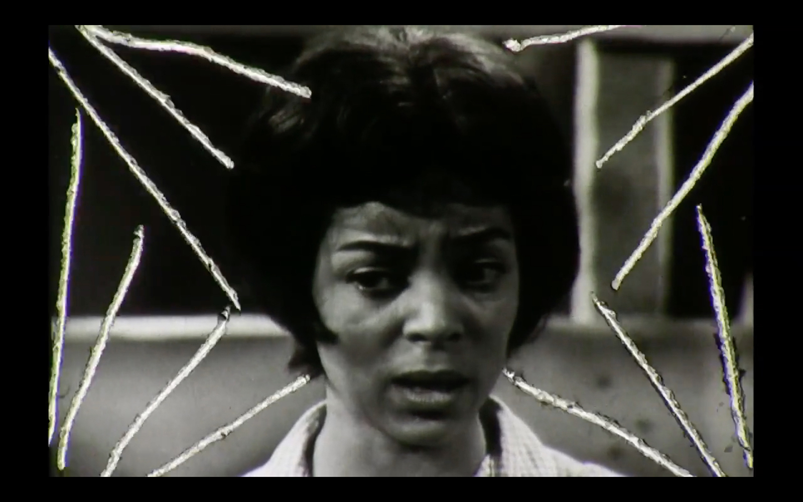 Film still with lines drawn from corners to central figure of a Black woman with a worried facial expression