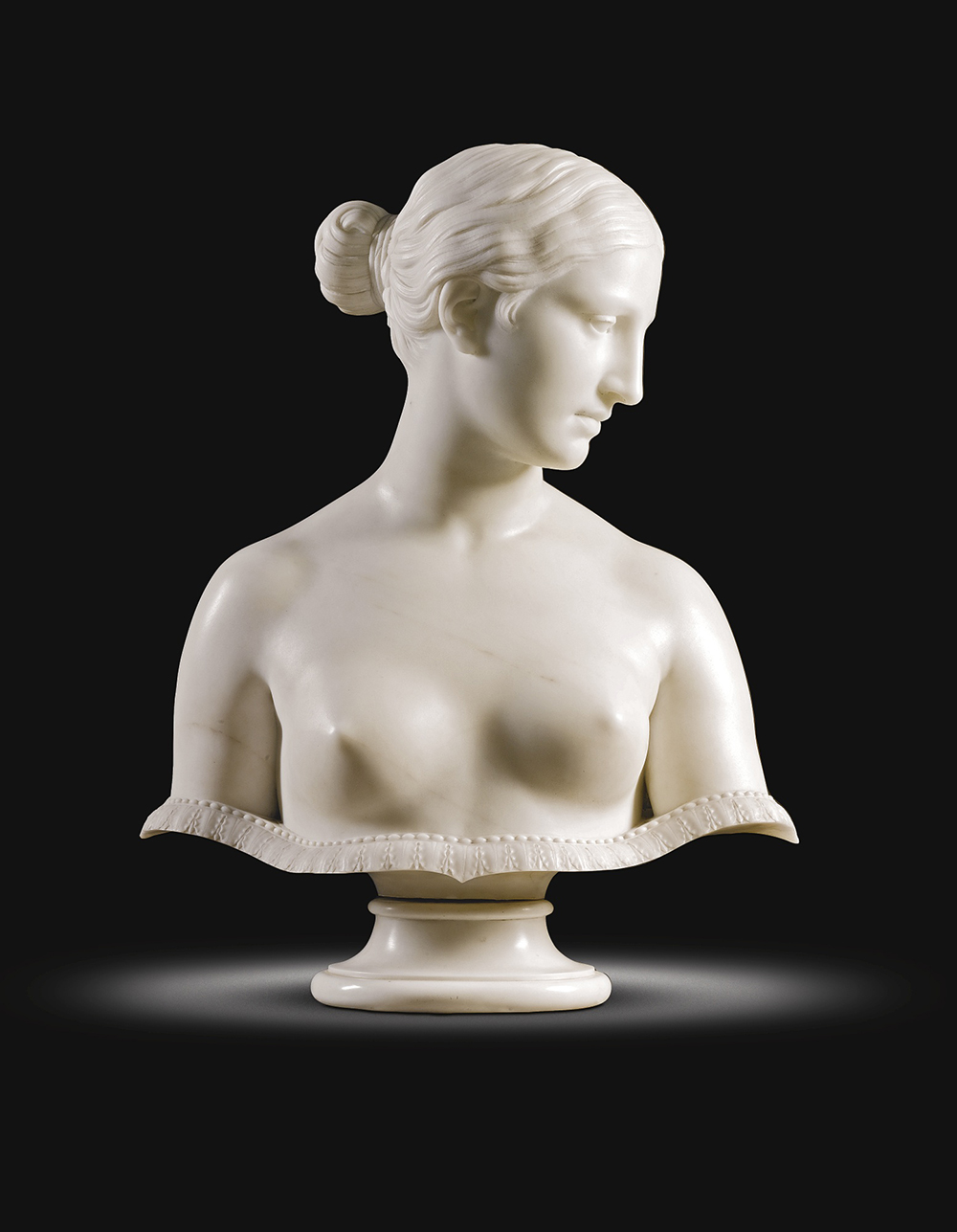 Marble half-length bust sculpture of nude woman wearing hair pulled back in a bun with head turned in profile. Acanthus leaf ornamentation beaded across the bottom of the half-length bust