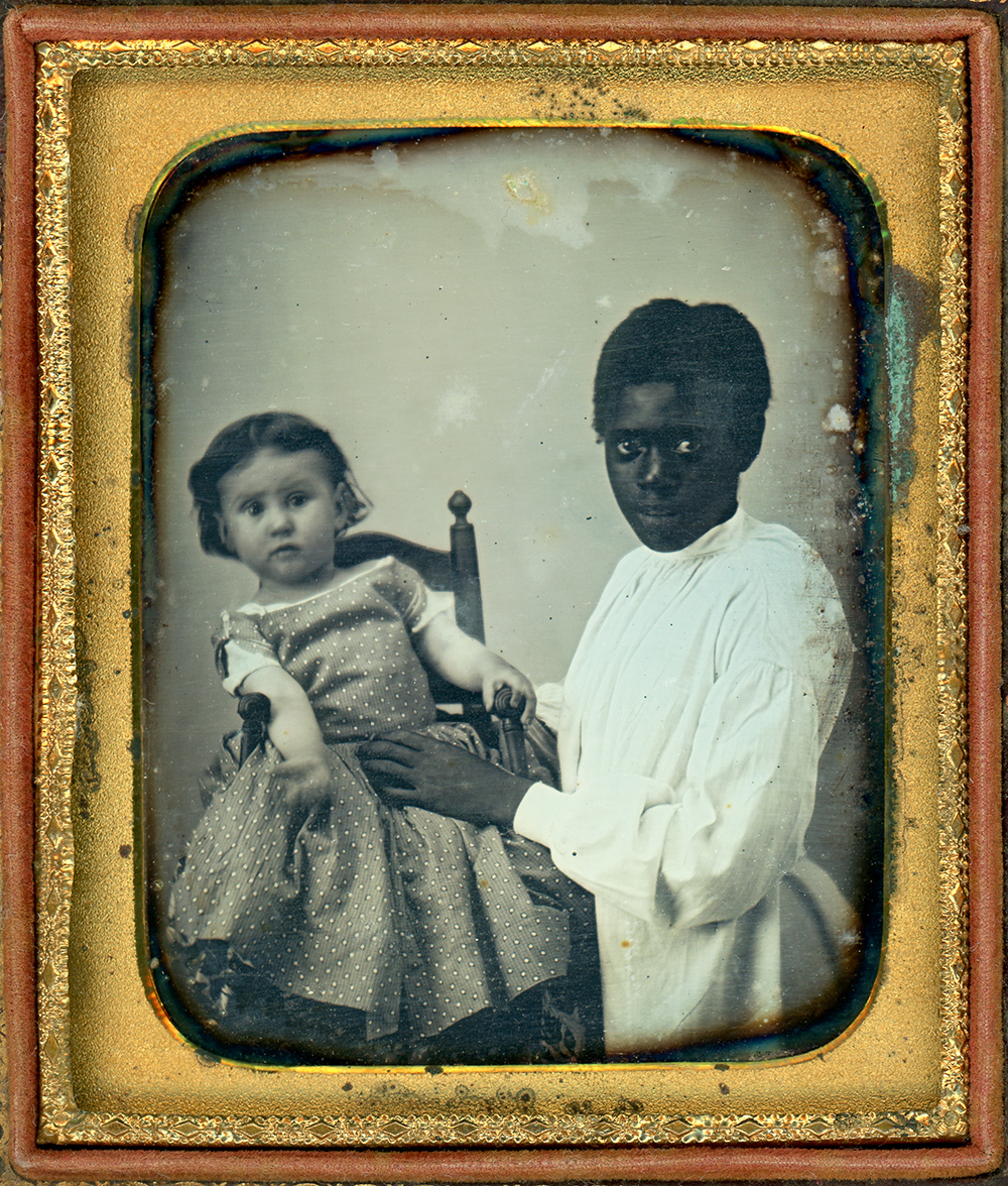 Daguerreotype portrait of a squirming white child seated in chair with enslaved Black girl staring directly at the viewer and holding the white child in place